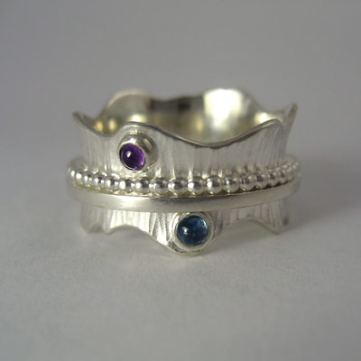 Spinner ring mommy's birth gift hammered wavy band beaded wire spinner sterling silver cabochon amethyst aquamarine
Daphne Meesters Jewellery Designer Goldsmith The Hague Netherlands
