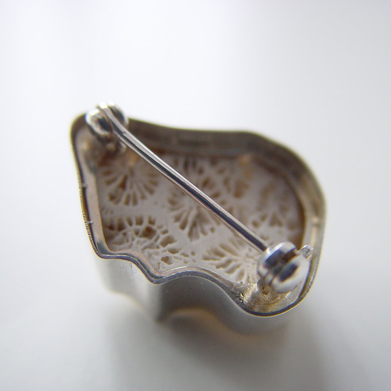 Titanic brooch irregular shape sterling silver rim around a white coral fossil representing the iceberg that destroyed the Titanic € 760,- Daphne Meesters Jewellery Designer Goldsmith The Hague Netherlands