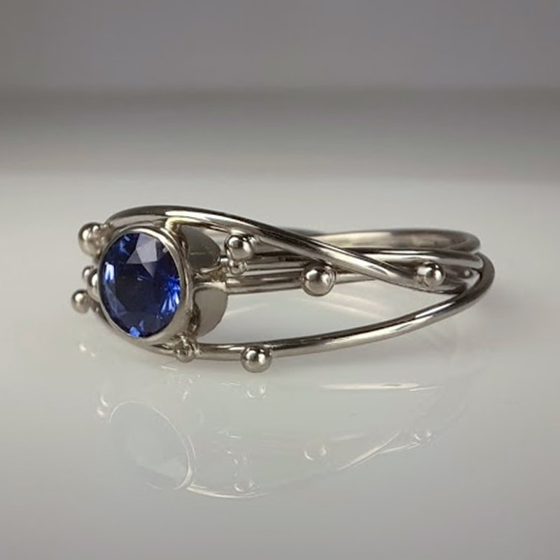 Birds nest engagement ring from 14 carat white gold wire and balls with stunning blue sapphire Daphne Meesters Jewellery Designer Goldsmith The Hague Netherlands