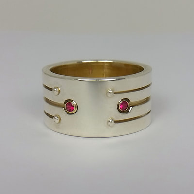 Engagement ring wide band with stripe pattern sterling silver 14K yellow gold and rubies faceted stones Soyuz 2 love you to the moon and back say yes proposal Daphne Meesters Jewellery Designer Goldsmith The Hague Netherlands
