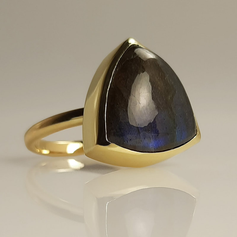 Trilliant memorial ring ashes jewellery from inherited 14K yellow gold with trilliant cut labradorite grey black with blue shine filled underneath with ashes of a deseased Daphne Meesters Jewellery Designer Goldsmith The Hague Netherlands