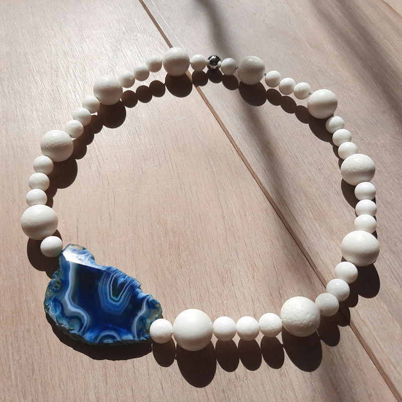 Slice ocean asymetric necklace of small and large white round coral beads with a slice of white and blue lined agate perfect summer wedding necklace  53.5 centimeters € 150,- Daphne Meesters Jewellery Designer Goldsmith The Hague Netherlands