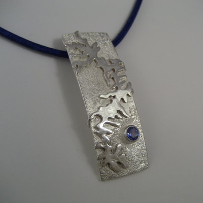 River of ice rectangular modern pendant reticulated sterling silver and faceted round blue tanzanite on blue leather string Daphne Meesters Jewellery Designer Goldsmith The Hague Netherlands